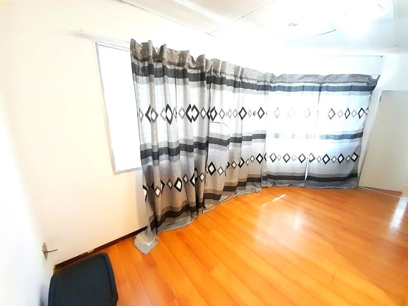 An empty living area featuring laminate flooring and ceiling tiles, awaiting personal touches to enhance the space.