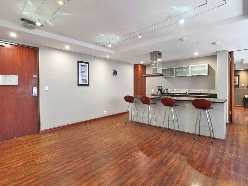 Open-plan living area featuring a kitchen with granite countertops, stainless steel extractor fan, and laminate flooring throughout.