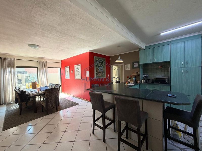 Open plan living and kitchen area featuring tiled flooring, a breakfast bar island, and sliding door access to the outdoor space.