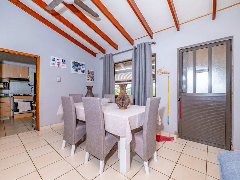 Dining area featuring exposed timber ceiling beams, tiled flooring, and direct access to the exterior through a glass-paneled door.