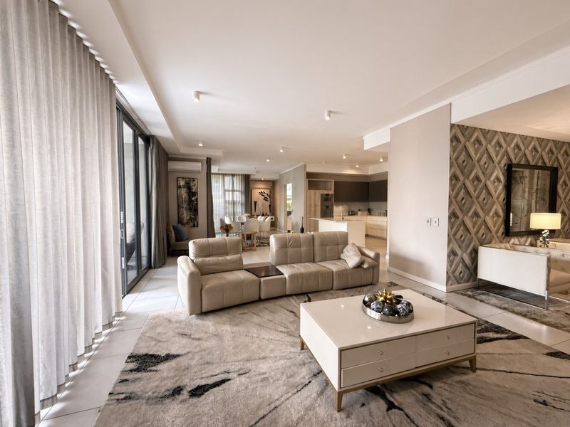 Spacious open-plan living area featuring modern tiled floors, recessed lighting, and a seamless flow to the kitchen, complemented by large sliding glass doors.
