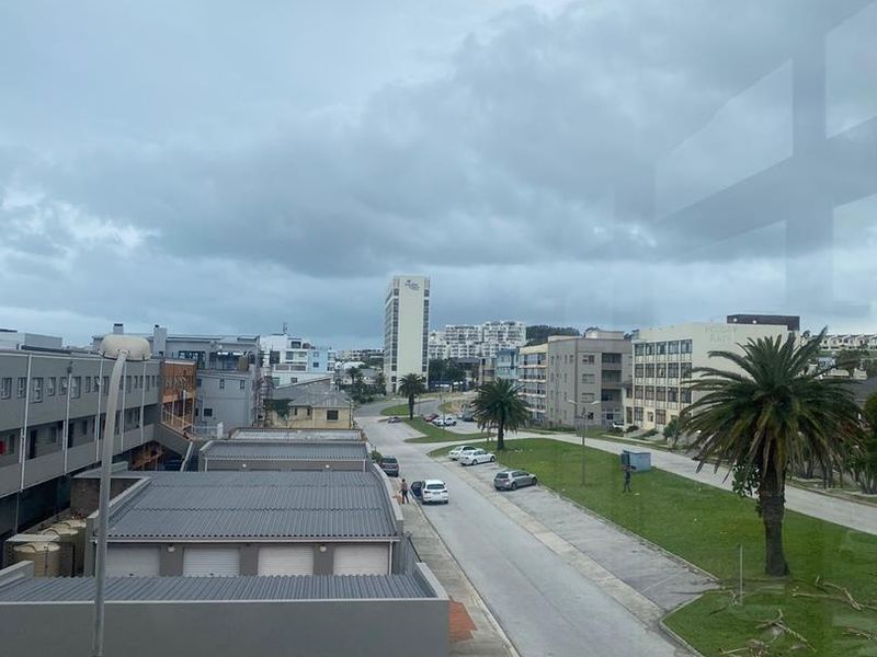 An elevated view overlooking the surrounding neighbourhood street, nearby apartment buildings, and local infrastructure under an overcast sky.