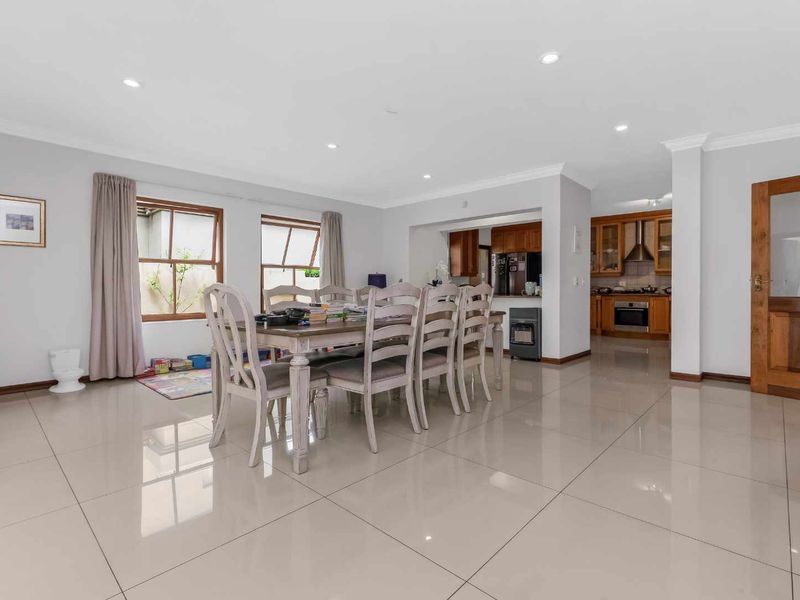 Spacious open-plan living and dining area featuring polished floor tiles, recessed lighting, and a functional timber kitchen with built-in appliances.
