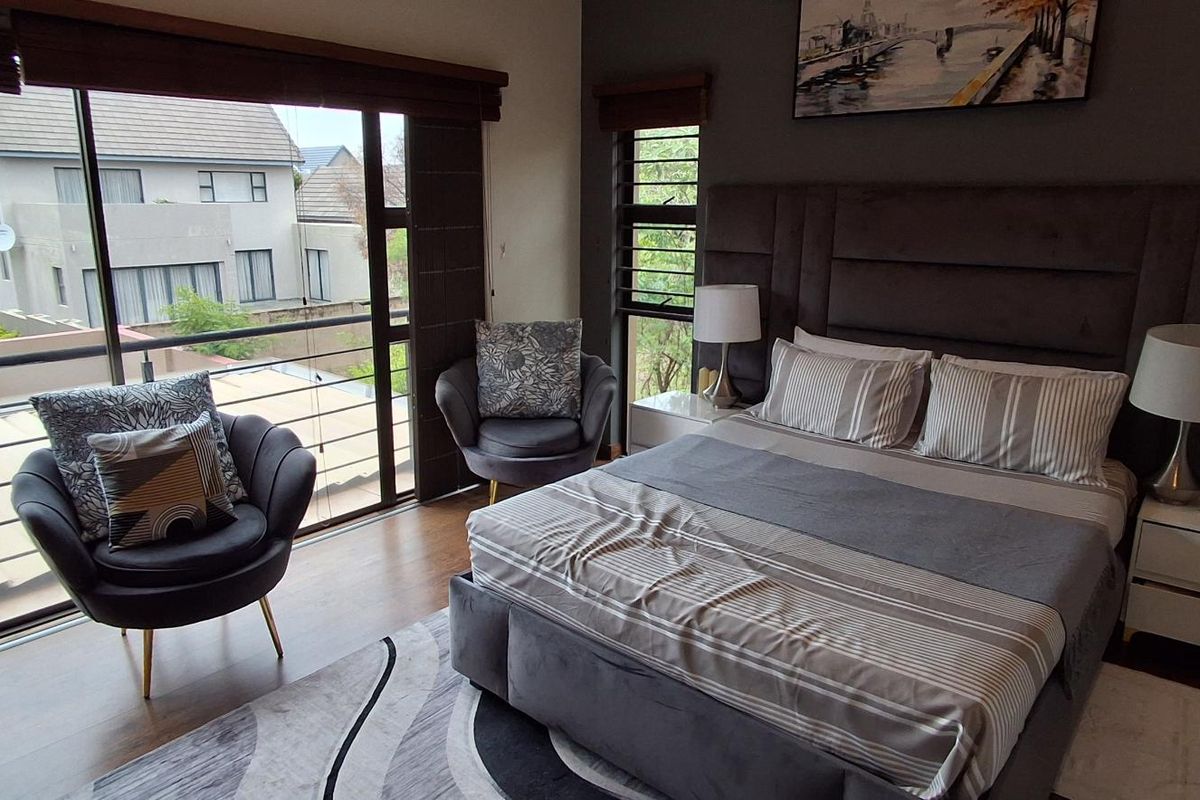 A well-appointed bedroom featuring large sliding glass doors that open to a balcony, providing natural light and views of the surrounding neighborhood.
