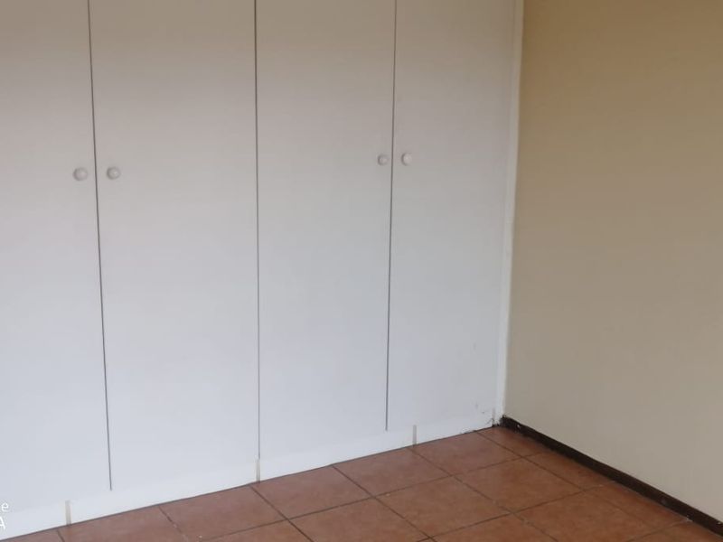 A simple, empty bedroom featuring built-in cupboards and tiled flooring, providing a blank canvas for personalization.