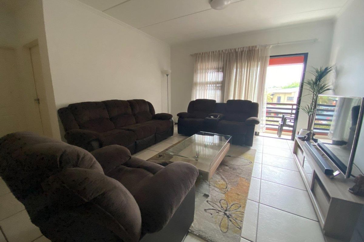 A living room featuring tiled flooring and a sliding glass door providing access to an outdoor balcony area.