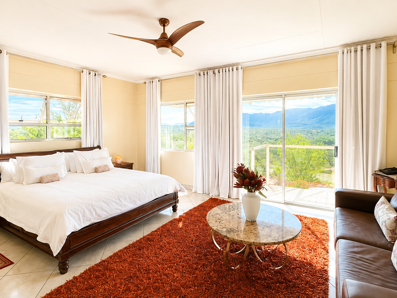 Spacious bedroom featuring tiled floors, a ceiling fan, and large sliding glass doors that open to scenic mountain views.