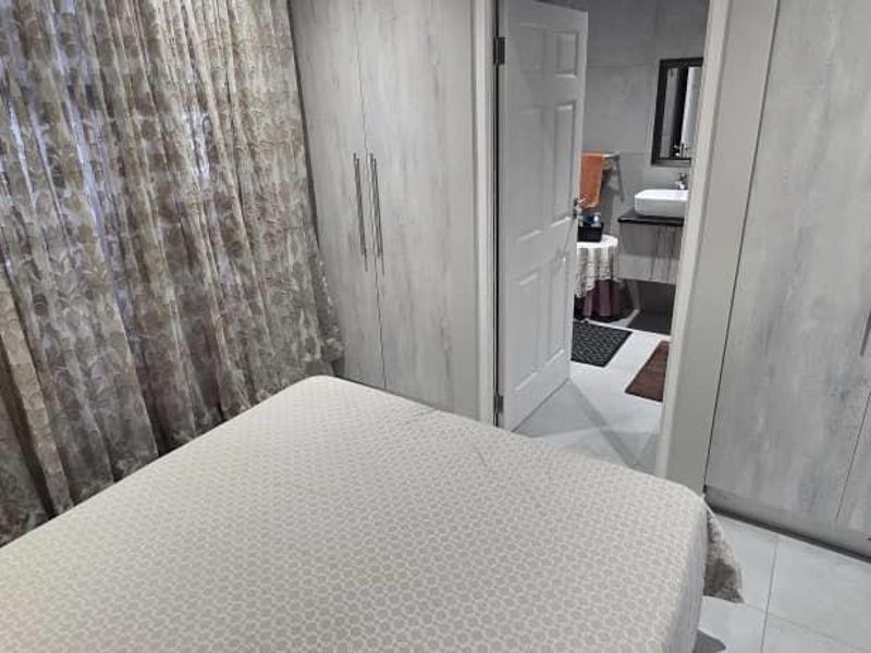A well-maintained bedroom featuring modern built-in cupboards, tiled flooring, and direct access to an en-suite bathroom.