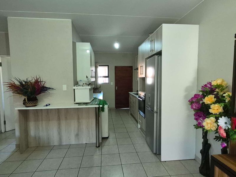 A functional kitchen featuring tiled flooring, built-in cabinetry, a breakfast bar, and integrated appliances, offering a practical layout for daily use.