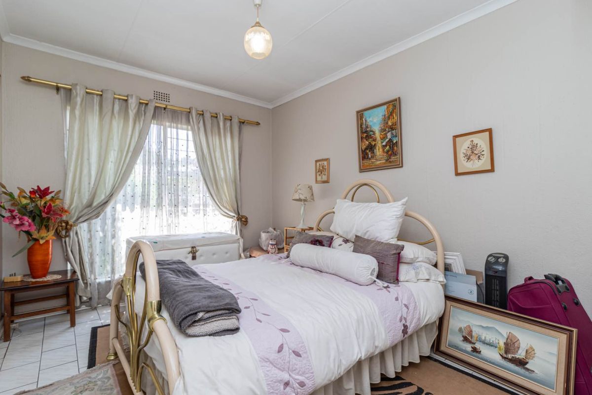 A bedroom featuring tiled flooring, a ceiling light fixture, and a window with curtain rod and curtains.