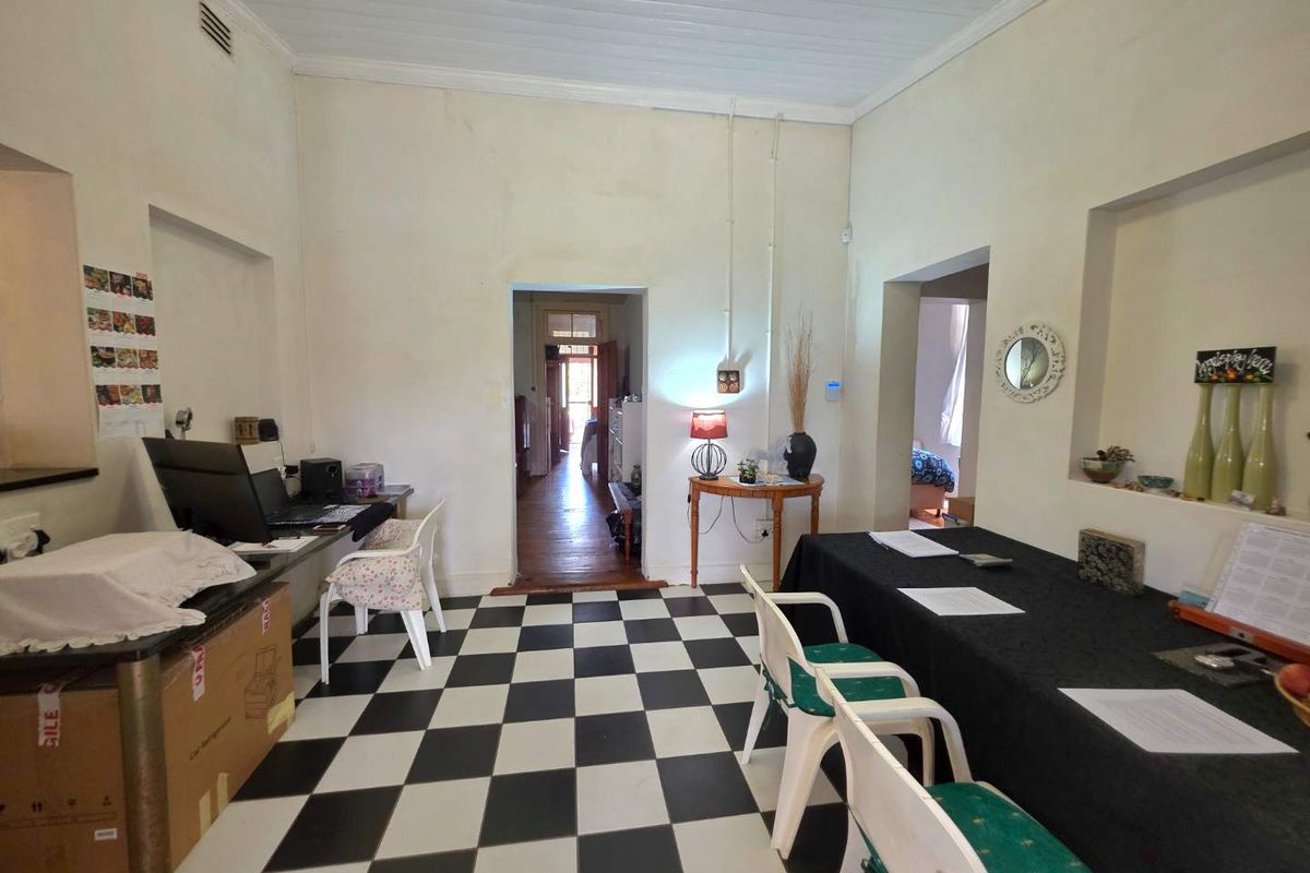 A multi-purpose room featuring a black and white checkered floor, high ceilings, and built-in wall niches, providing access to adjacent living areas.