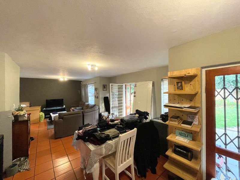 Open-plan living and dining area featuring terracotta floor tiles, direct garden access through a security gate, and neutral wall tones.