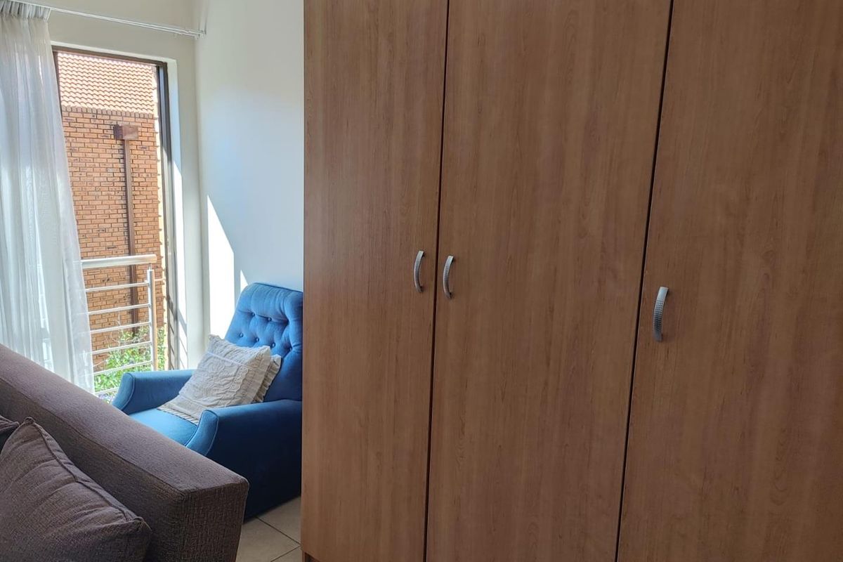 A bedroom featuring a large built-in wooden wardrobe, tiled flooring, and direct access to a small balcony area.