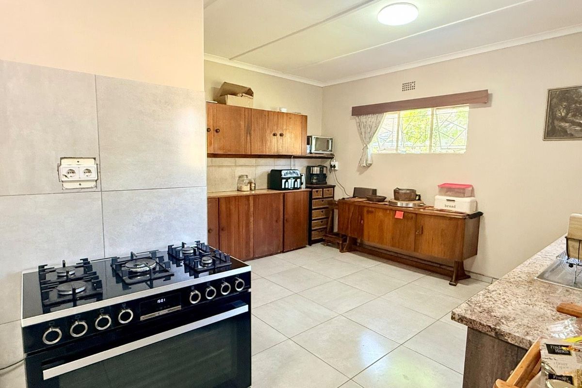 A functional kitchen featuring tiled flooring, wooden cabinetry, and a modern freestanding gas stove with oven.