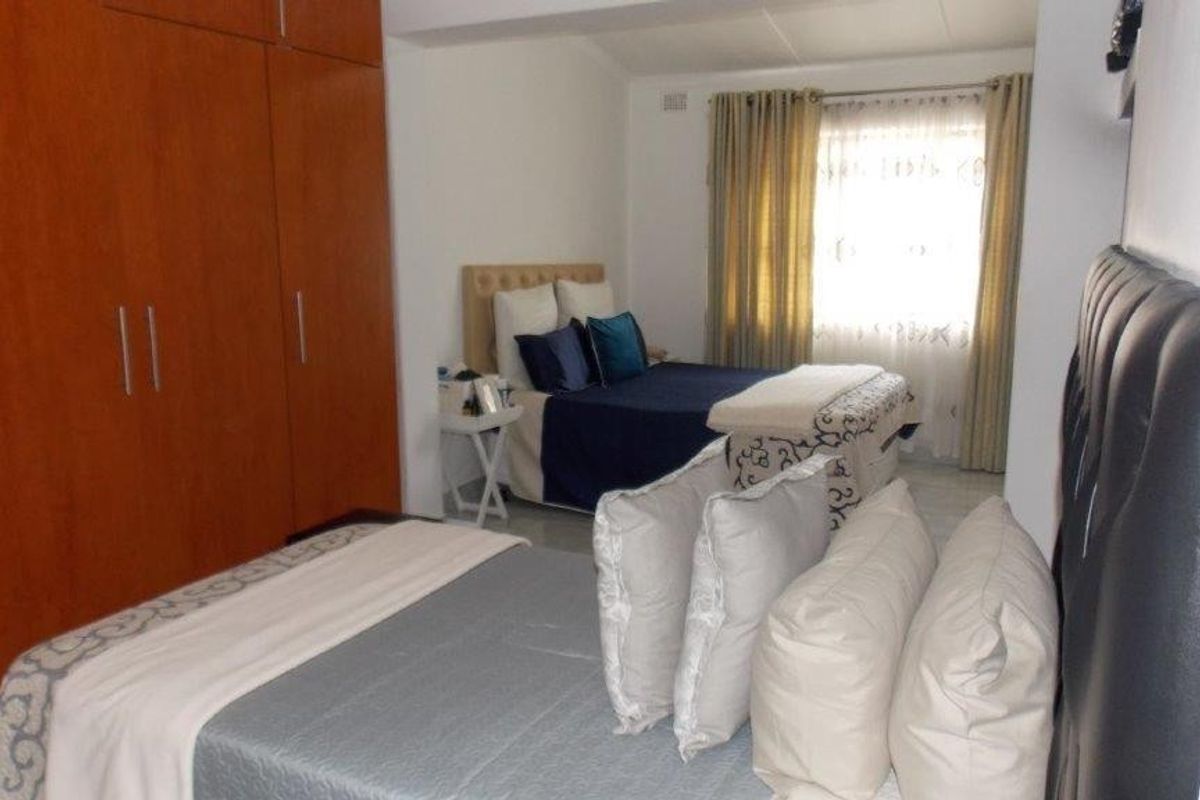 A bedroom featuring built-in wooden cupboards and natural light from a window with curtains.