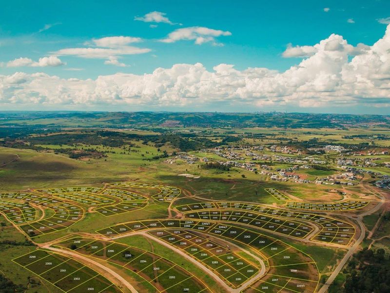 An aerial view of a large residential land development site showing subdivided plots and surrounding landscape.