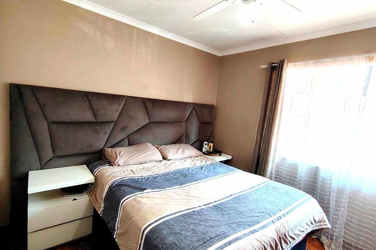 A bedroom featuring a ceiling fan, tiled flooring, and a large window with natural light.