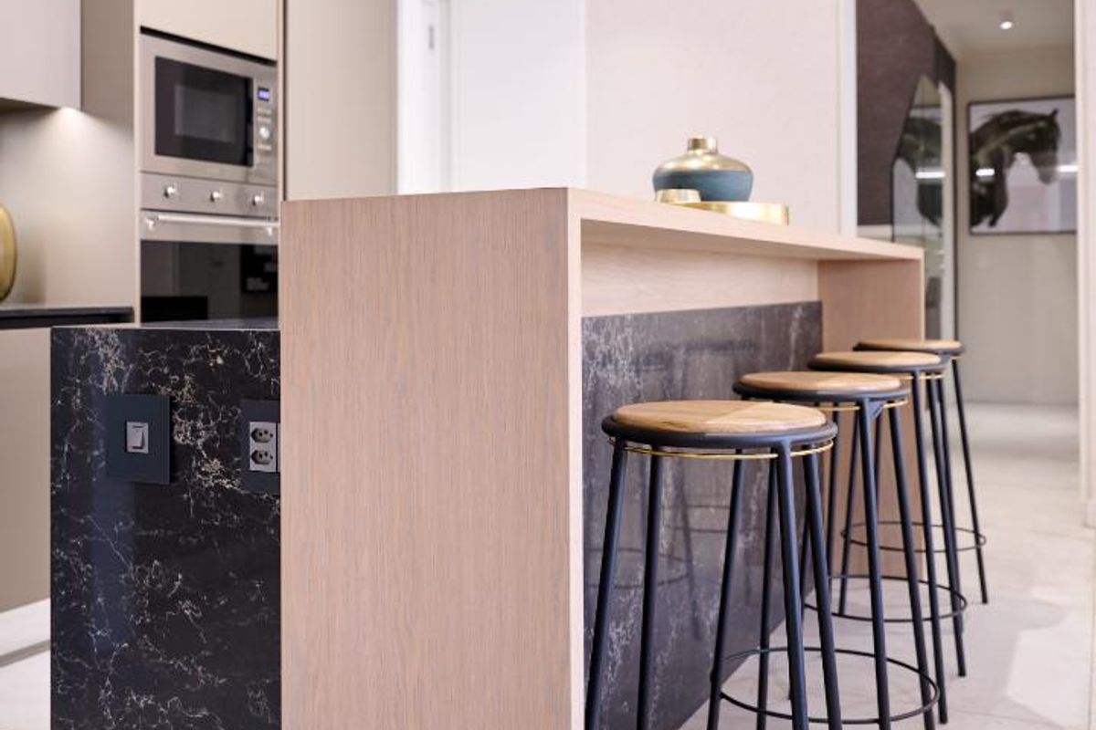 Modern kitchen featuring a waterfall edge stone island, integrated oven, microwave, and sleek cabinetry with recessed ceiling lighting.