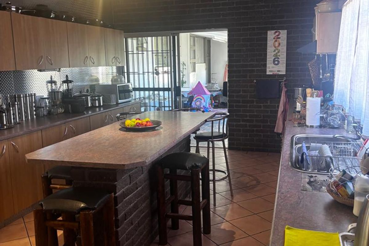 Spacious kitchen featuring a central brick-based island, laminate countertops, ample cabinetry, and direct access to the outdoor patio area.