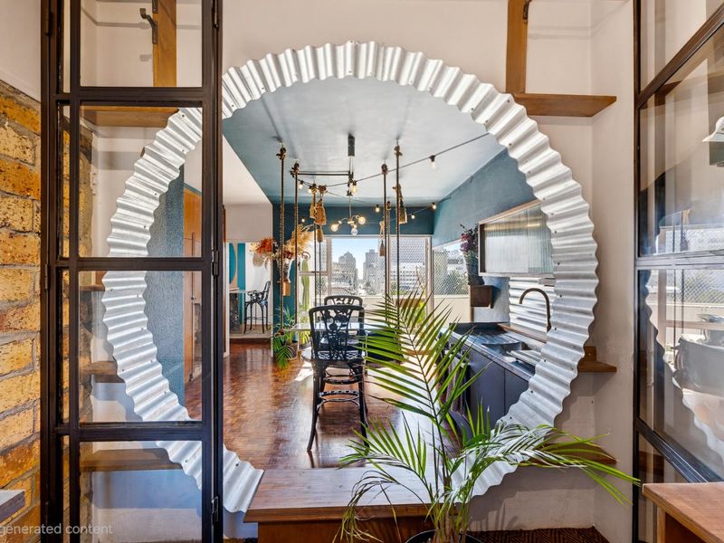 A unique open-plan living and kitchen area featuring a striking circular corrugated metal architectural element, parquet flooring, and industrial-style metal-framed glass partitions.