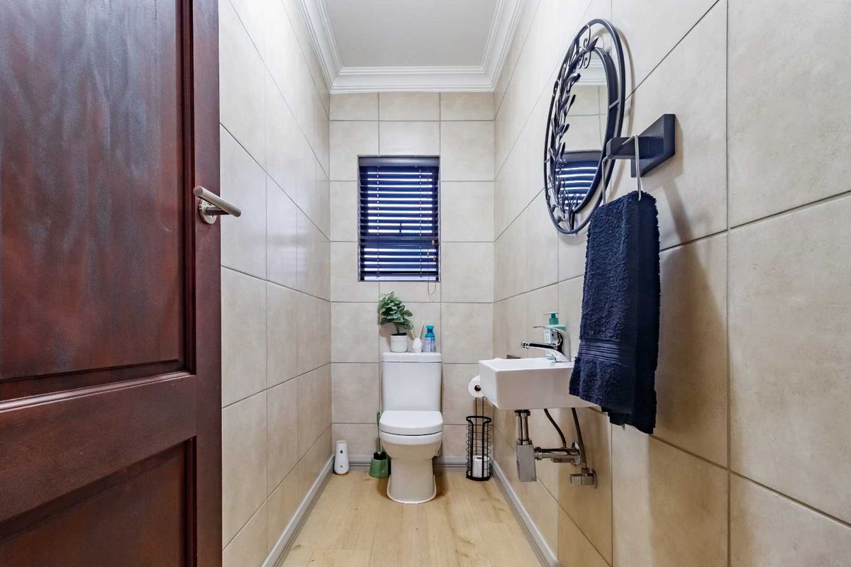 A compact guest bathroom featuring floor-to-ceiling wall tiles, a wall-mounted basin, and a modern toilet.