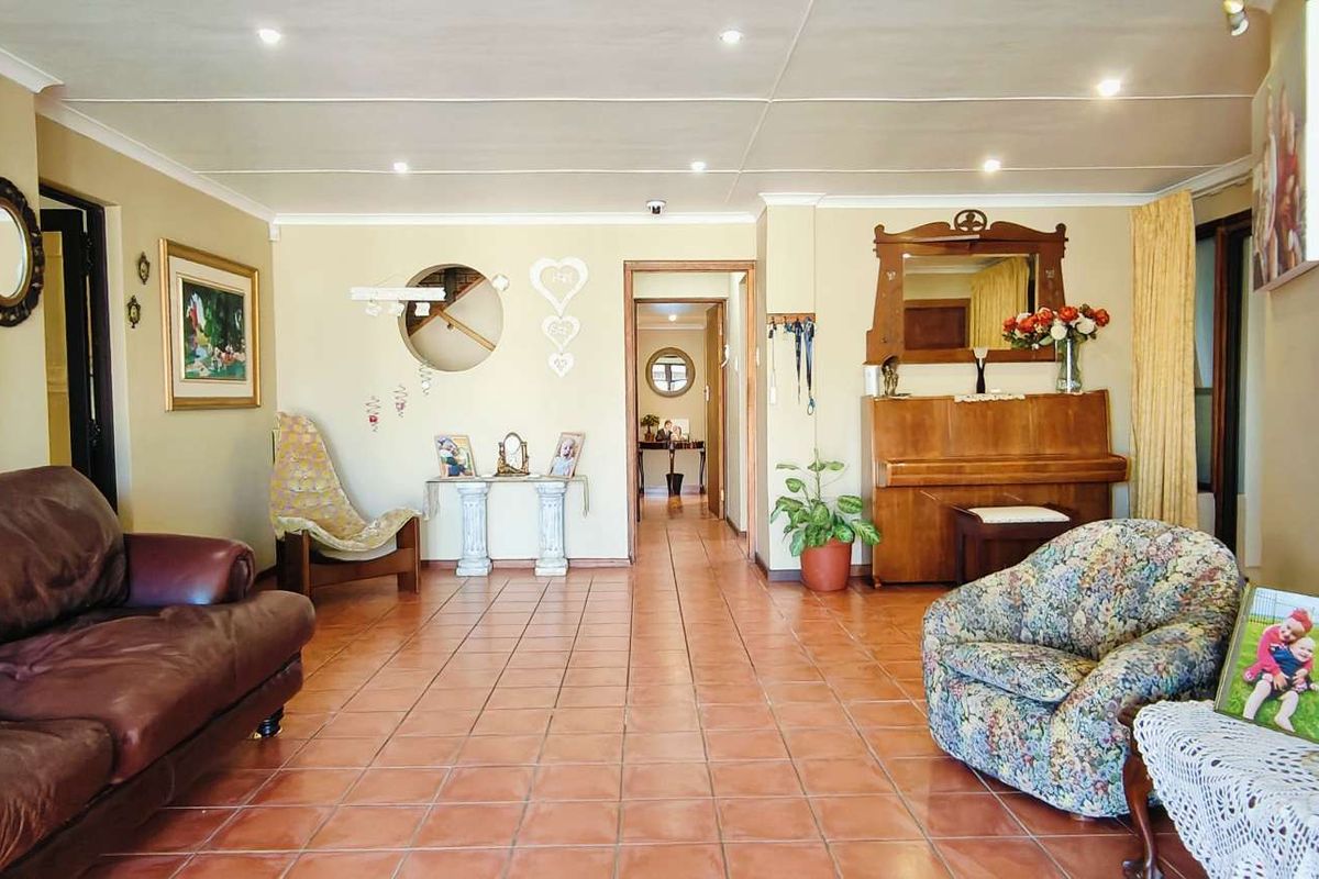 A spacious living room featuring tiled flooring, recessed ceiling lighting, and a neutral color palette, providing a comfortable and functional living area.