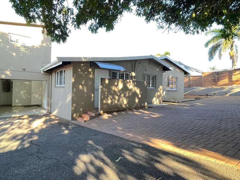 Front exterior view of the property featuring a paved driveway, attached garage, and secure entrance area with an awning.