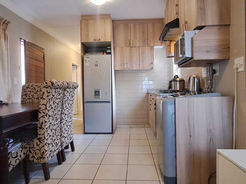 Open-plan living and kitchen area featuring light wood-finish cabinetry, tiled flooring, and a functional layout suitable for modern living.