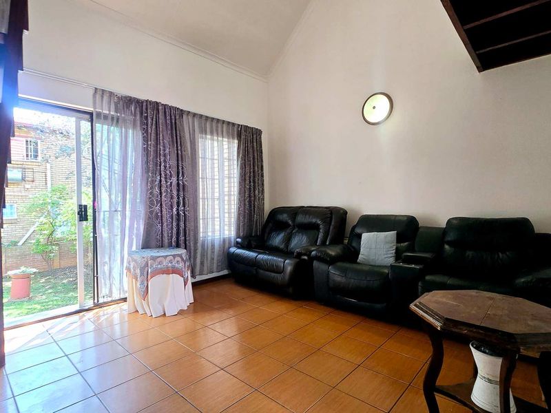 A living room featuring tiled flooring, a vaulted ceiling, and a staircase, with a sliding glass door providing access to the exterior.
