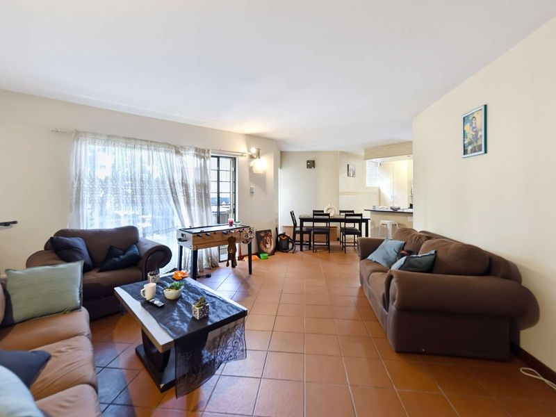 Spacious open-plan living and dining area featuring tiled flooring, a breakfast counter, and direct access to the patio through a sliding glass door.