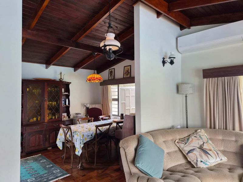 Open-plan living and dining area featuring exposed timber ceiling beams, parquet flooring, and a wall-mounted air conditioning unit.