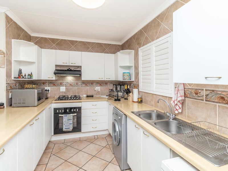 Functional kitchen featuring white cabinetry, laminate countertops, gas hob, built-in oven, and a double bowl stainless steel sink with tiled backsplash.