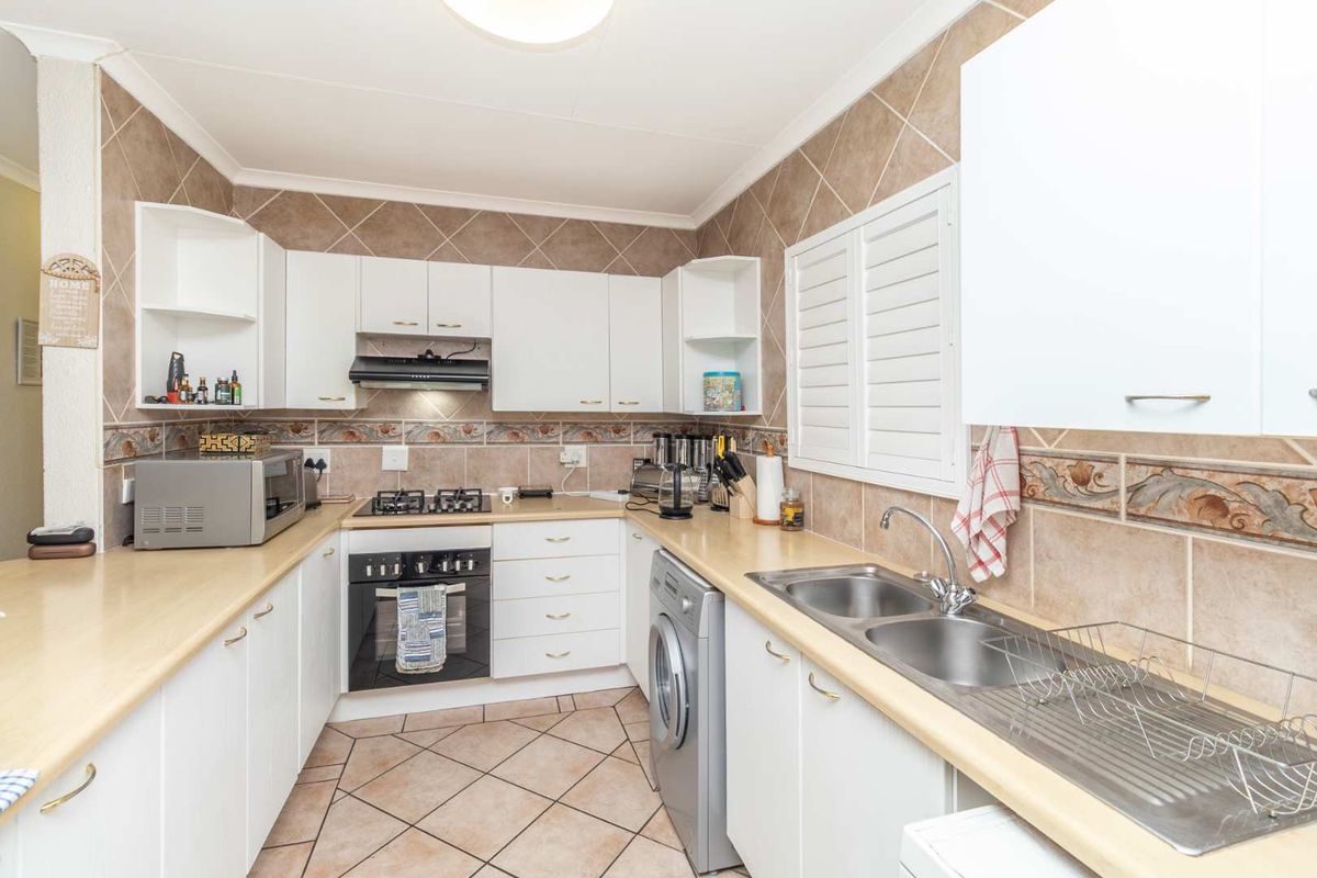Functional kitchen featuring white cabinetry, laminate countertops, gas hob, built-in oven, and a double bowl stainless steel sink with tiled backsplash.