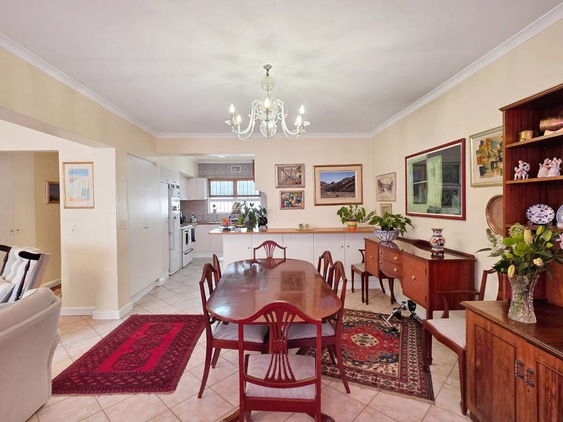 Spacious open-plan dining and kitchen area featuring ceramic tile flooring, a breakfast bar, and classic cabinetry, offering a functional layout for daily living.
