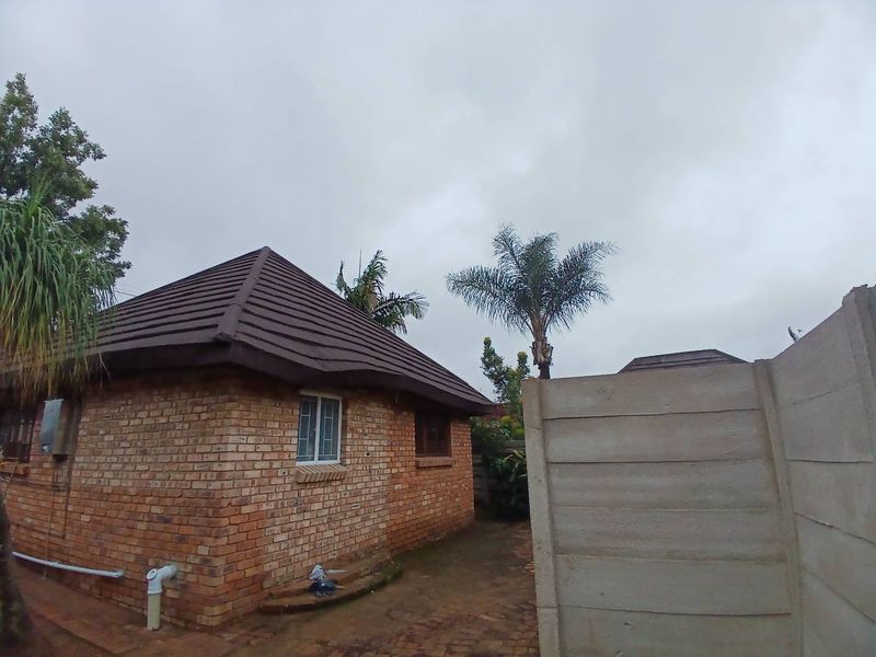 Rear view of a face brick cottage featuring a tiled roof and a precast concrete boundary wall.