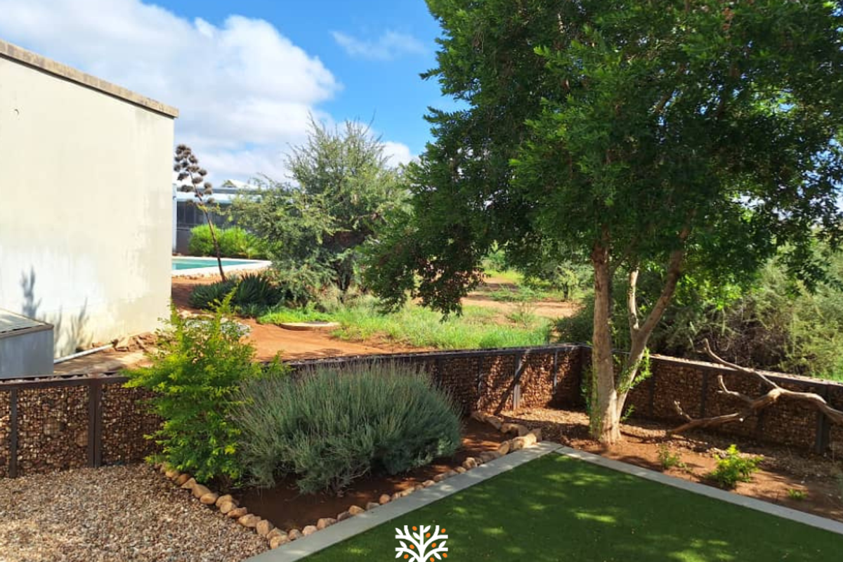 A well-maintained rear garden featuring gabion retaining walls, artificial turf, and established trees, providing a private outdoor space.