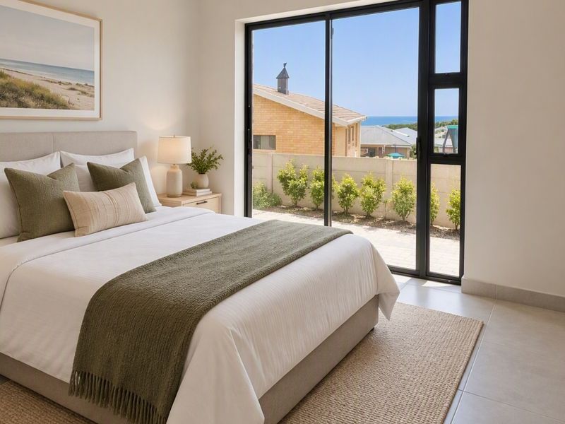 Modern bedroom featuring built-in cupboards, tiled flooring, and large sliding glass doors providing natural light and access to the exterior.
