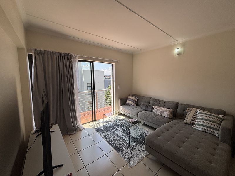 A living room featuring tiled flooring and a sliding glass door providing access to an outdoor balcony area.