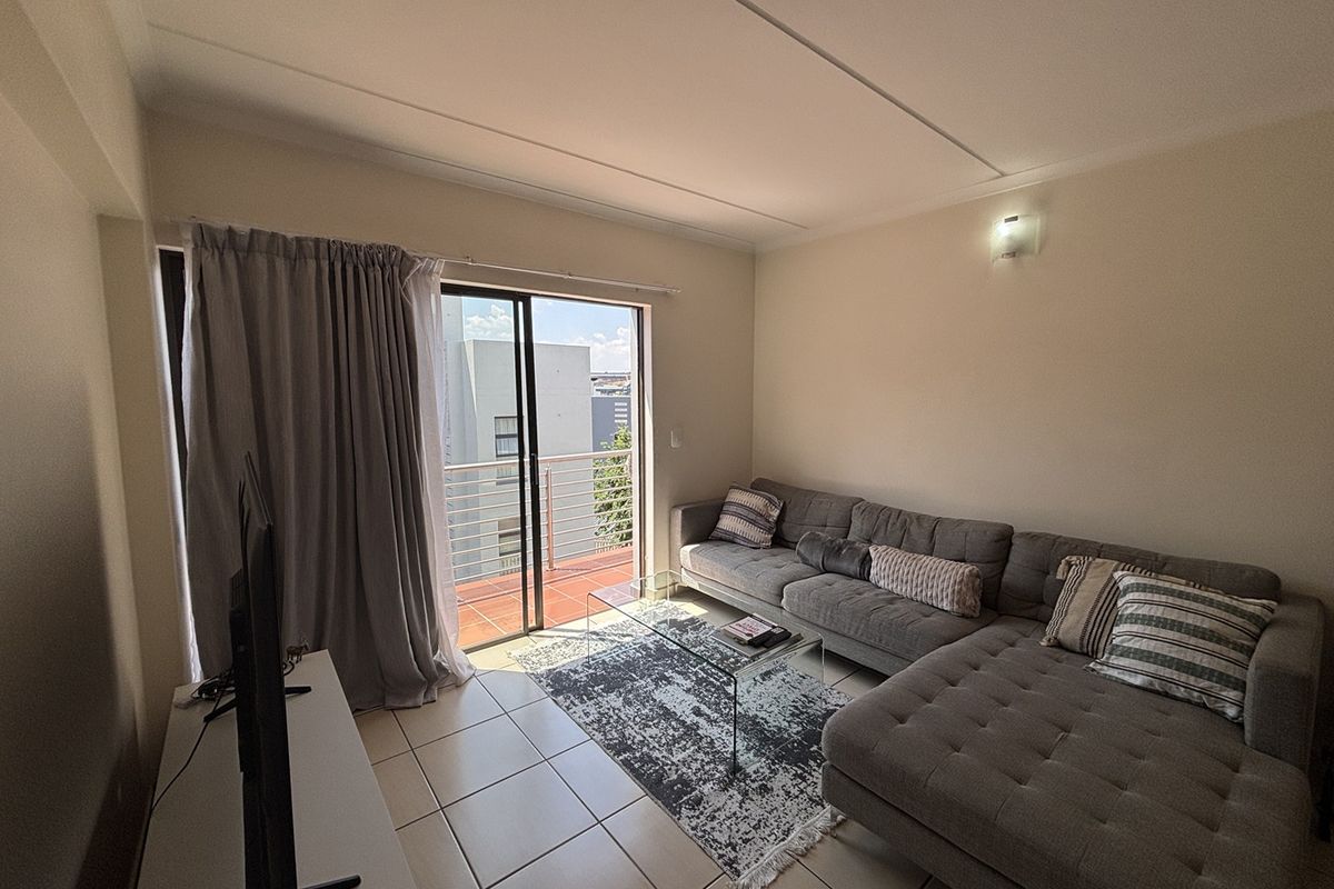 A living room featuring tiled flooring and a sliding glass door providing access to an outdoor balcony area.
