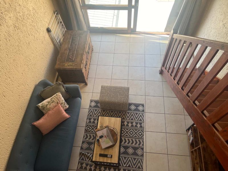 A living area featuring tiled flooring, a wooden staircase, and a sliding glass door providing access to the exterior.