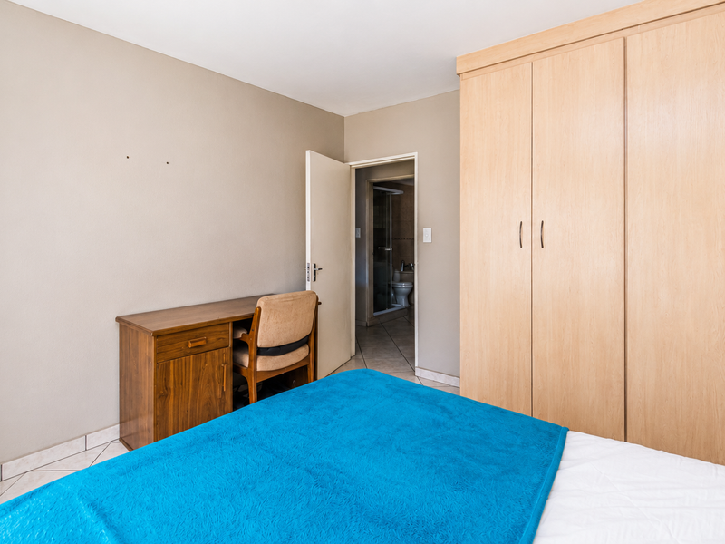 Bedroom featuring light wood built-in cupboards, tiled flooring, and direct access to an en-suite bathroom.