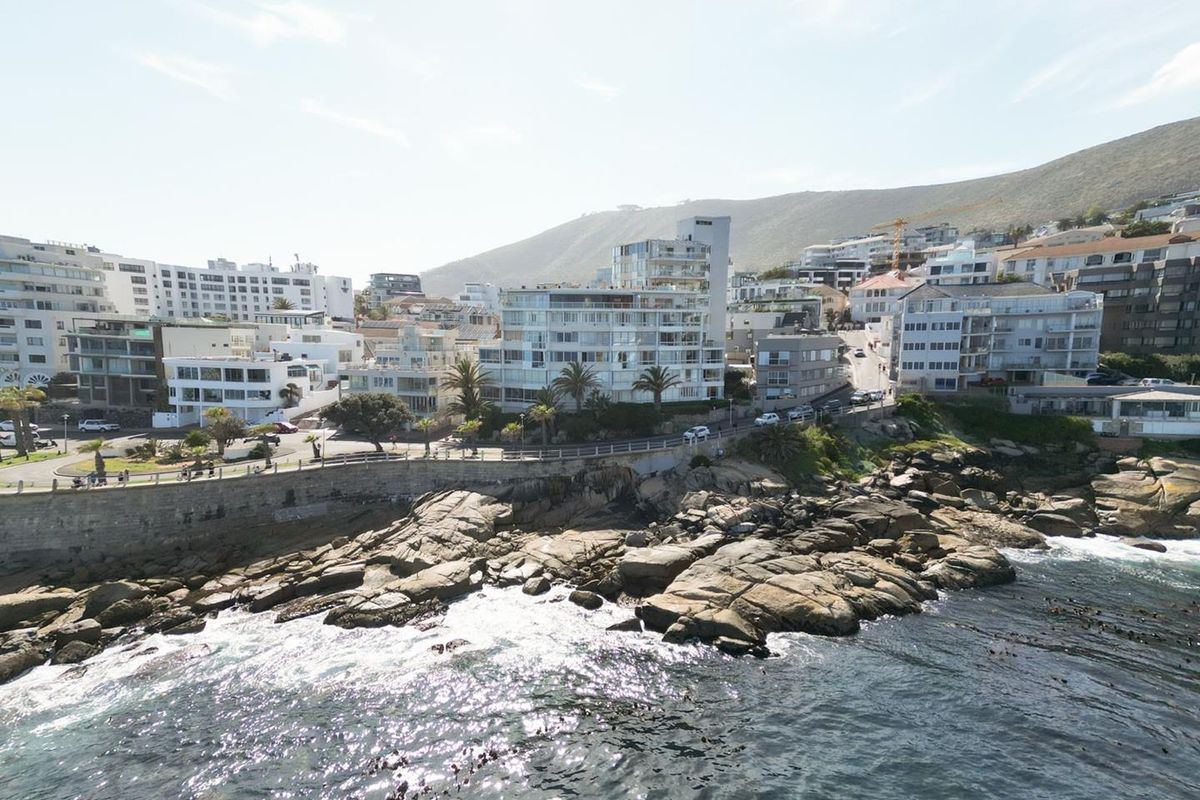 An aerial view of the coastal residential area, showcasing the proximity of the apartment buildings to the rocky shoreline and ocean.