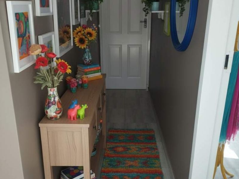 A well-maintained hallway featuring light-toned laminate flooring and a neutral wall finish, leading to an internal door.