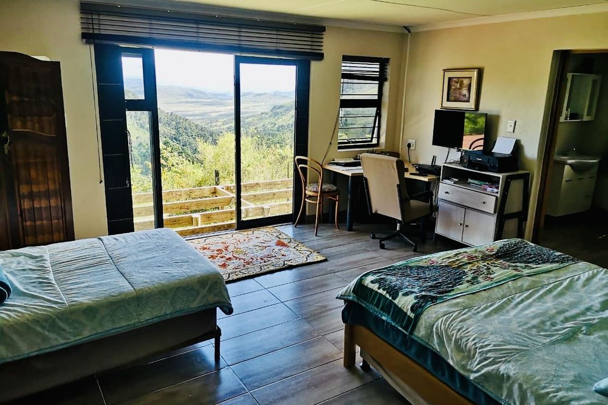 Spacious bedroom featuring tiled flooring, large sliding glass doors opening to a scenic mountain view, and an attached en-suite bathroom.