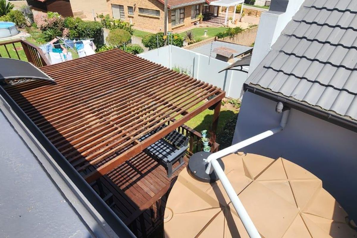 Elevated view of the rear garden featuring a timber pergola, wooden decking, and a large water storage tank.