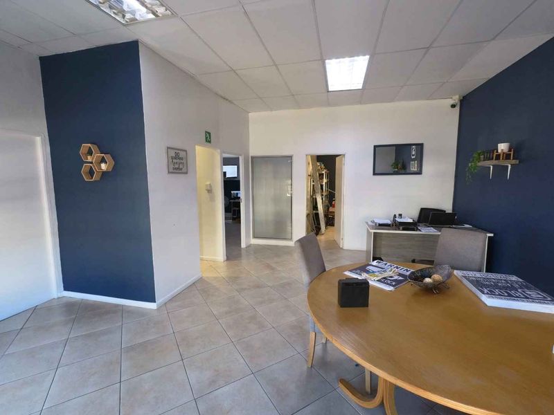 A functional office space featuring tiled flooring, a suspended ceiling with recessed lighting, and multiple internal access points.