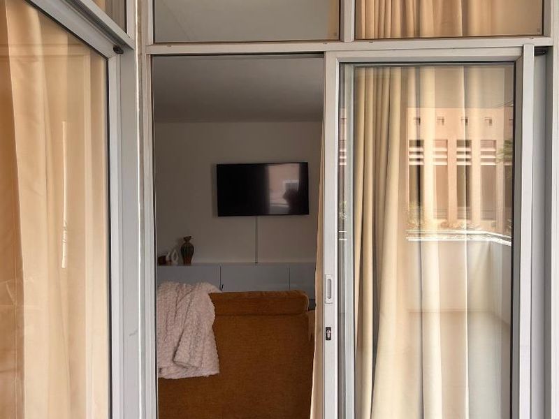 A covered balcony area featuring tiled flooring and aluminium sliding glass doors providing access to the interior living space.