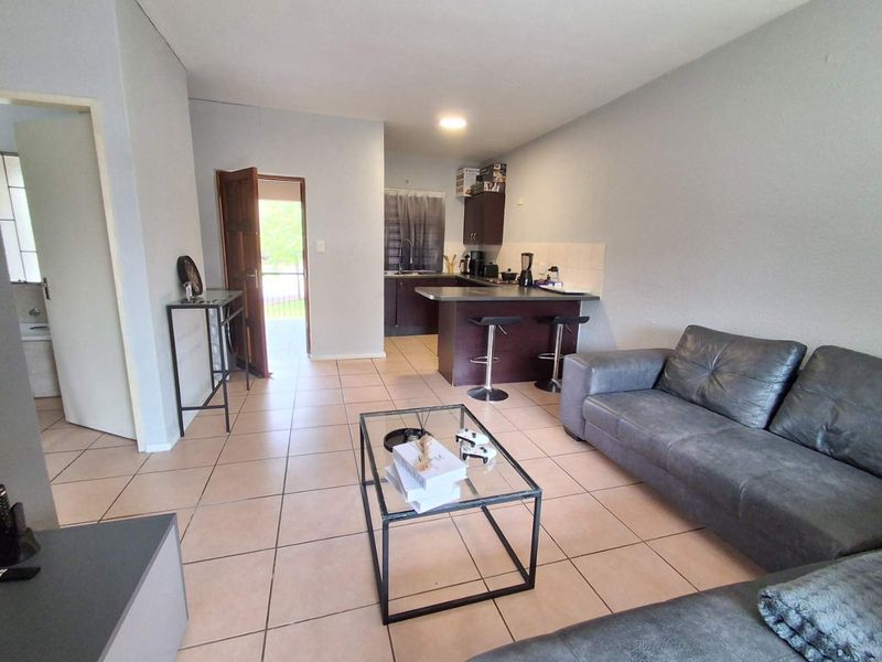 Open plan living area featuring tiled flooring and a functional kitchen with breakfast nook, providing a versatile space for daily living.