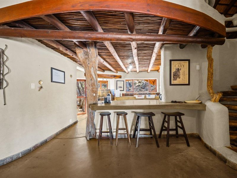 Open plan living area featuring rustic exposed timber beam ceilings, a concrete breakfast bar, and natural wood structural elements.