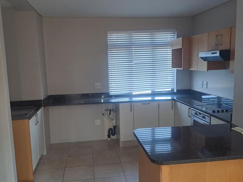 A functional kitchen featuring granite countertops, built-in oven, extractor fan, and ample cabinetry. The space is currently vacant and ready for personalization.